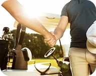 Two people shaking hands near a golf cart in a sunny outdoor setting.