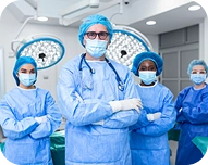 Four medical professionals in blue surgical attire and masks standing confidently in an operating room.