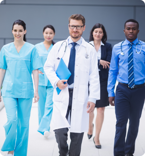 Group of diverse healthcare professionals, including doctors and nurses, walking confidently towards the camera.