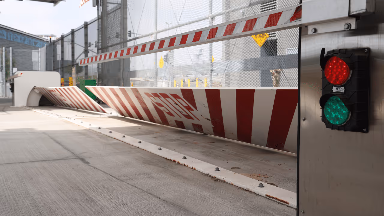 Security checkpoint barrier with 'STOP' sign and traffic light showing green light.