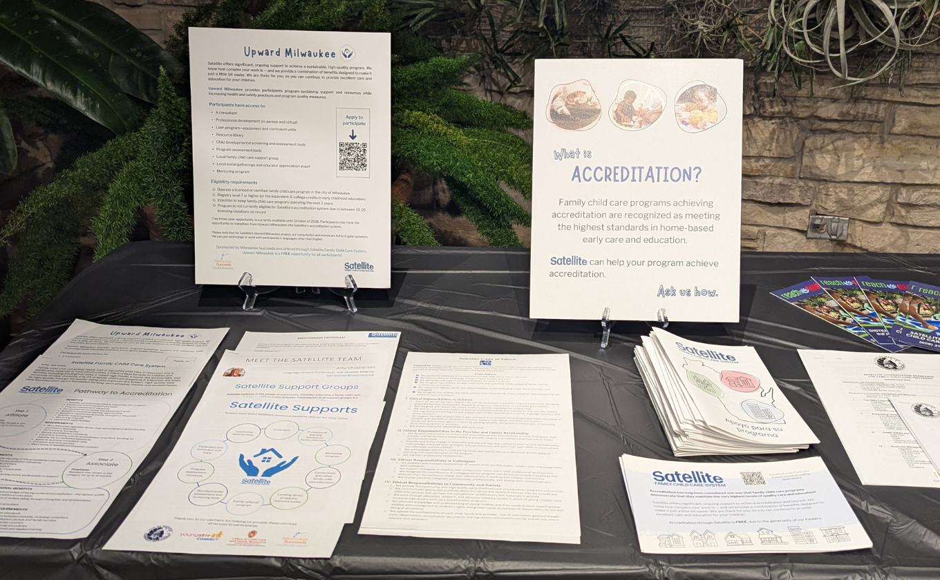 Table display of brochures and posters about Satellite child care accreditation and Upward Milwaukee program.