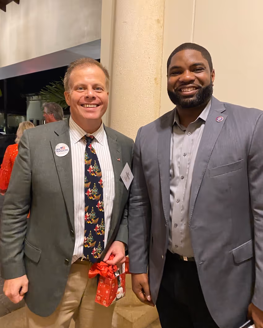 Two men smiling and posing indoors.