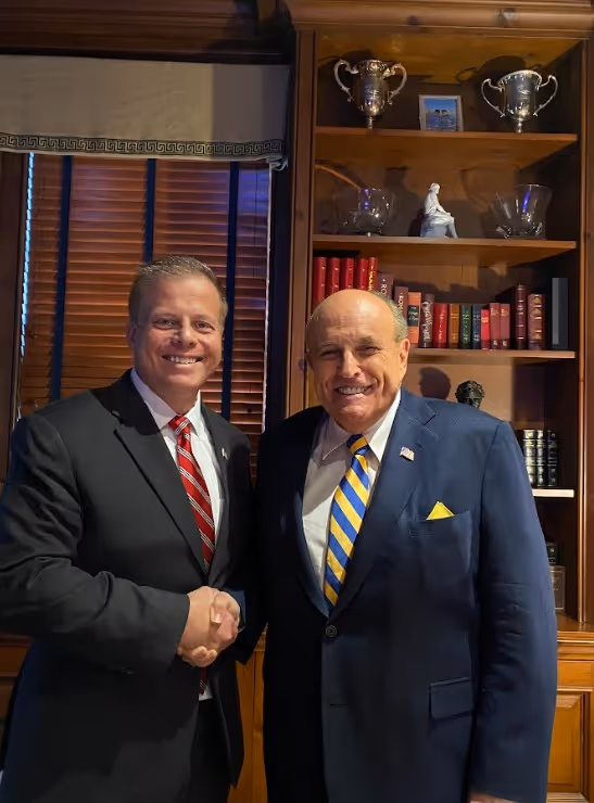 Two people smiling outdoors wearing Dan Franzese for Congress t-shirts and holding campaign flyers.
