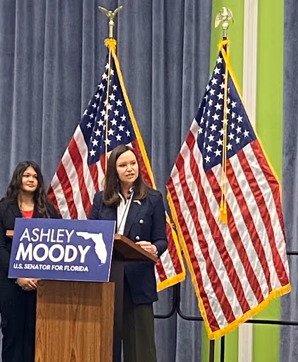 Two people smiling outdoors wearing Dan Franzese for Congress t-shirts and holding campaign flyers.