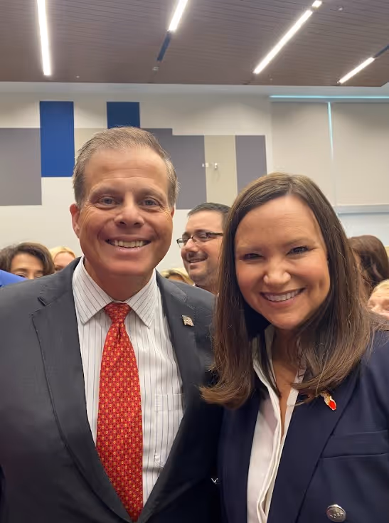 Two people smiling outdoors wearing Dan Franzese for Congress t-shirts and holding campaign flyers.