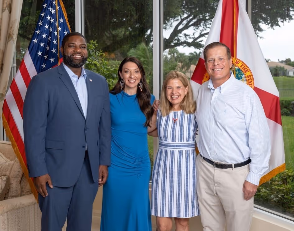 Two people smiling outdoors wearing Dan Franzese for Congress t-shirts and holding campaign flyers.