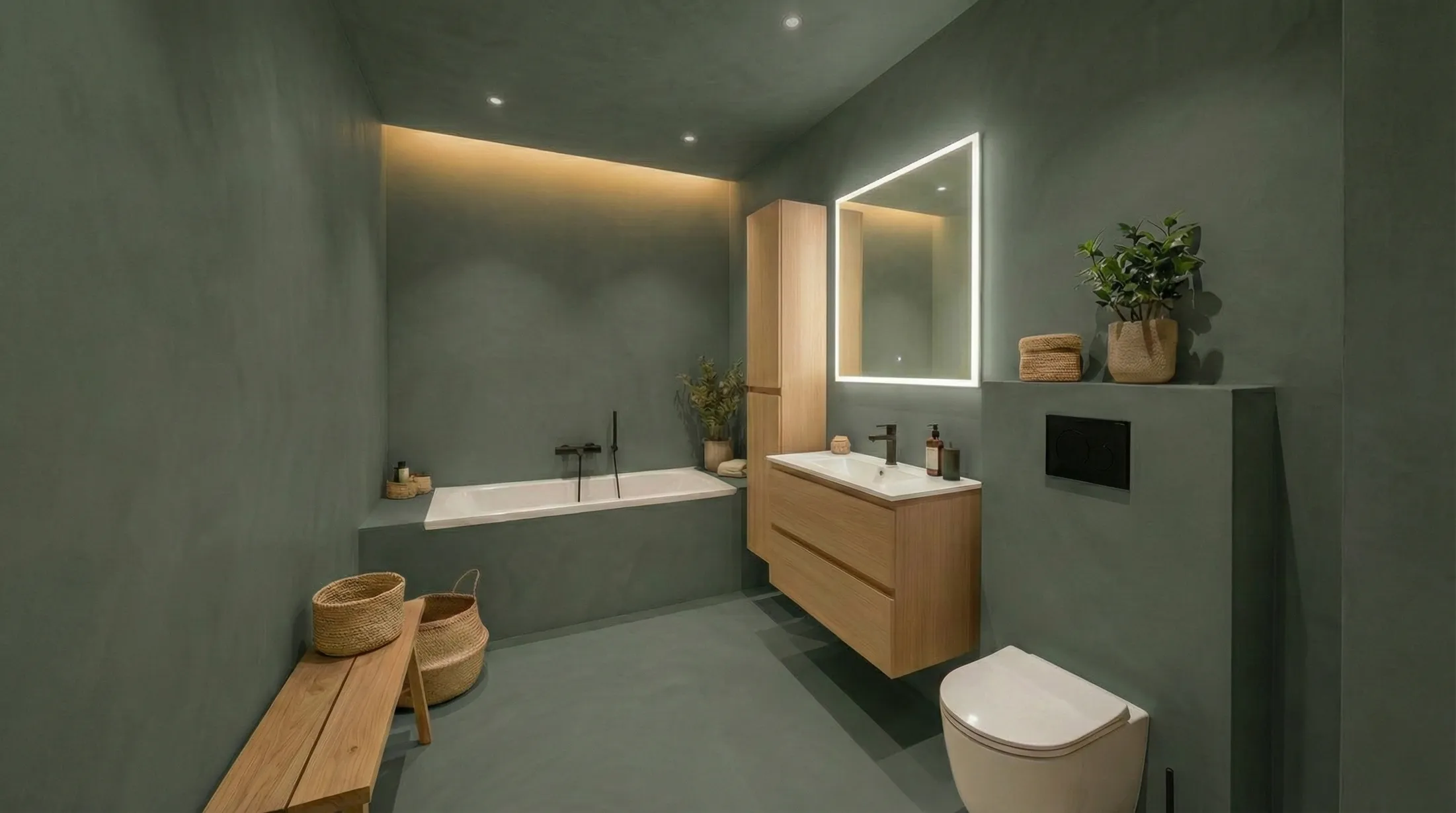 Modern bathroom with green walls, a built-in bathtub, wooden floating vanity, illuminated mirror, white toilet, and wicker baskets.