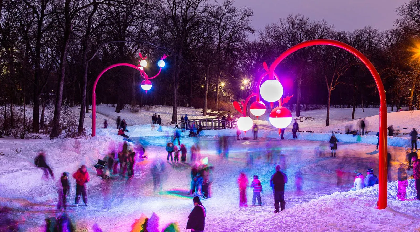 A group of people are standing in the snow in front of a lit up tunnel.