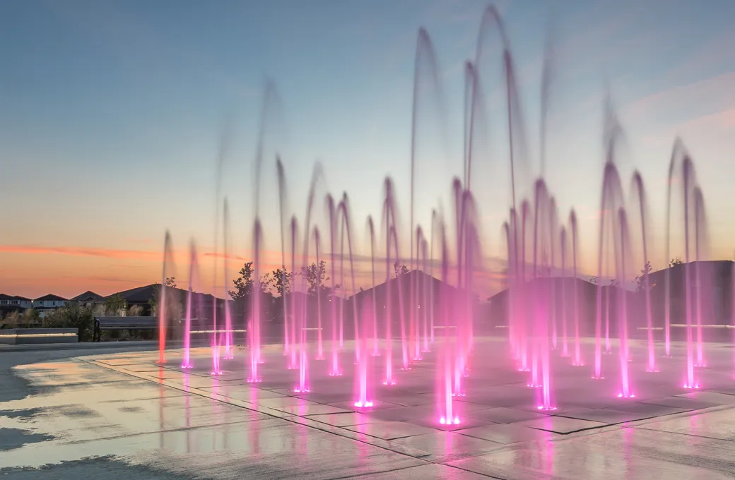 A fountain with pink water and purple lights.