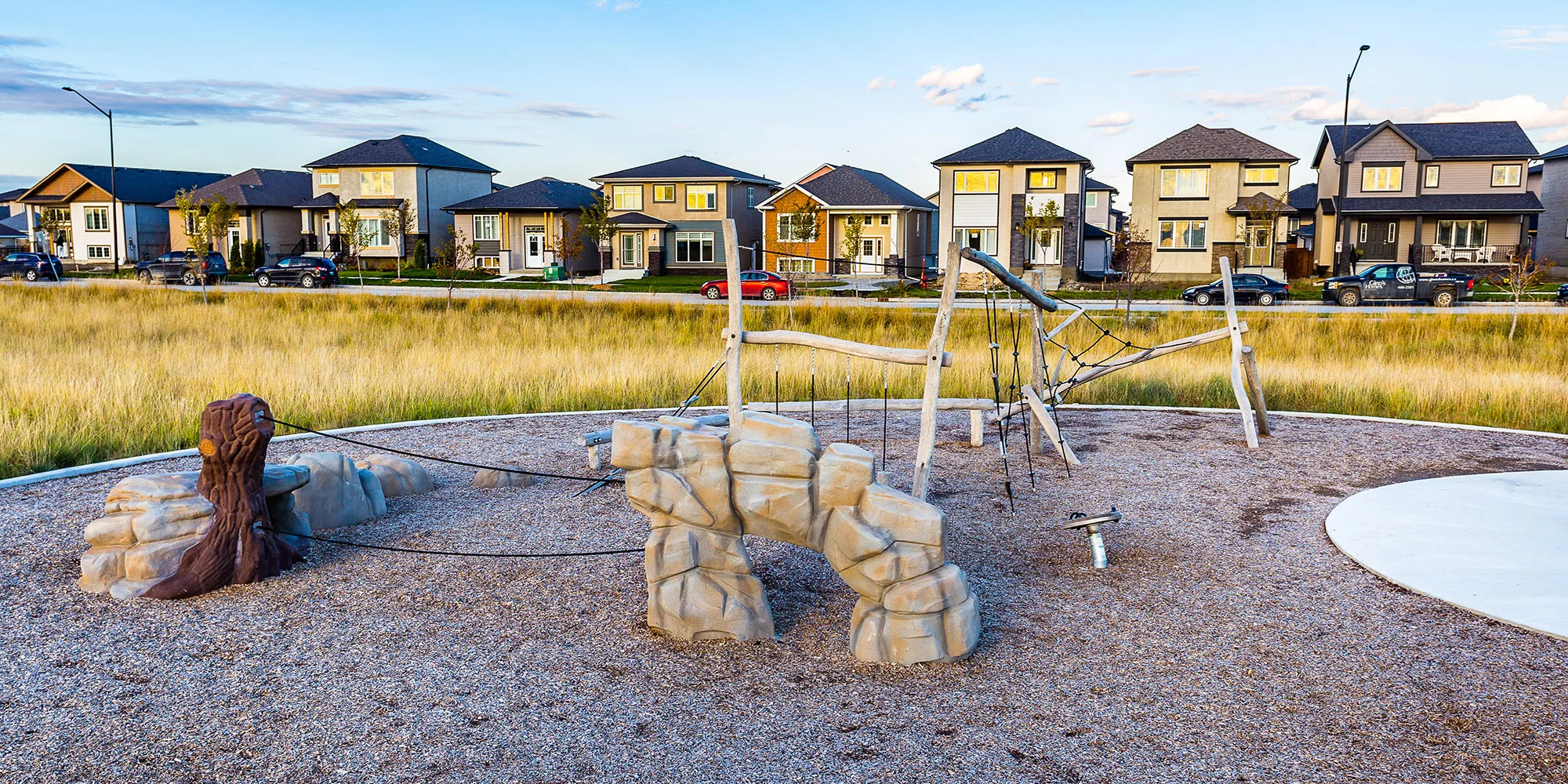 A playground with a large rock and a wooden bear.