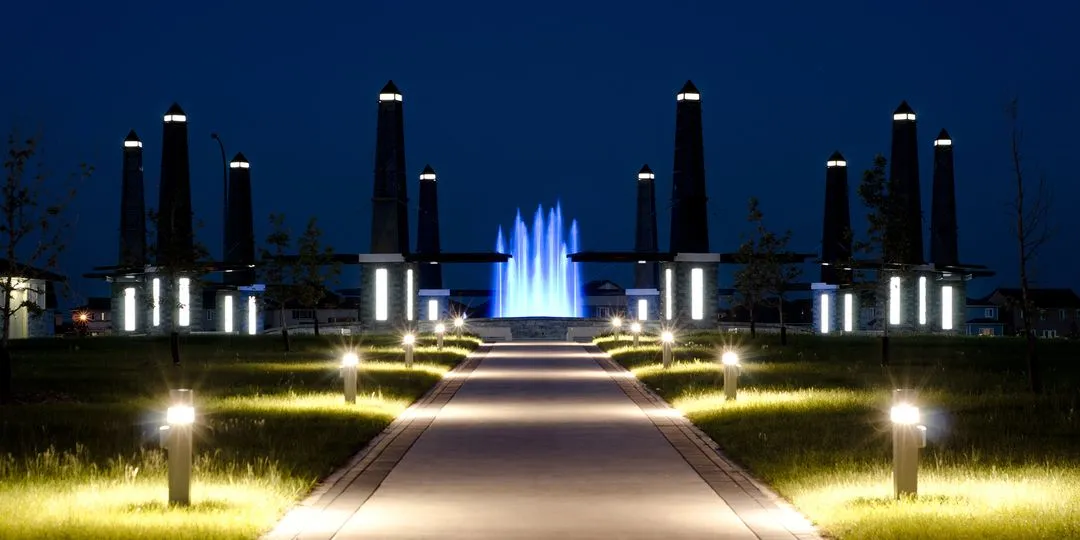 A pathway with a blue lighted fence and a blue lighted tower.