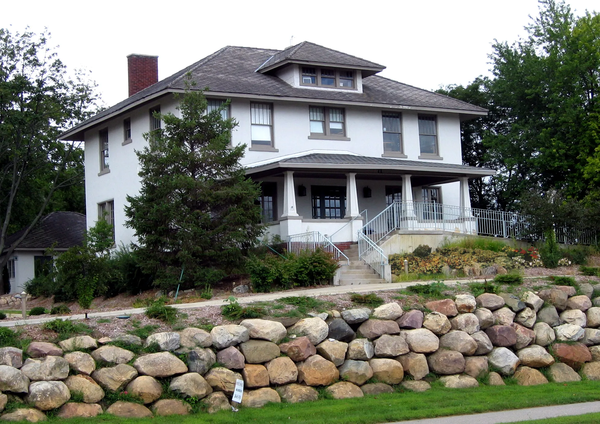 A large white house with a red brick chimney and a white roof.