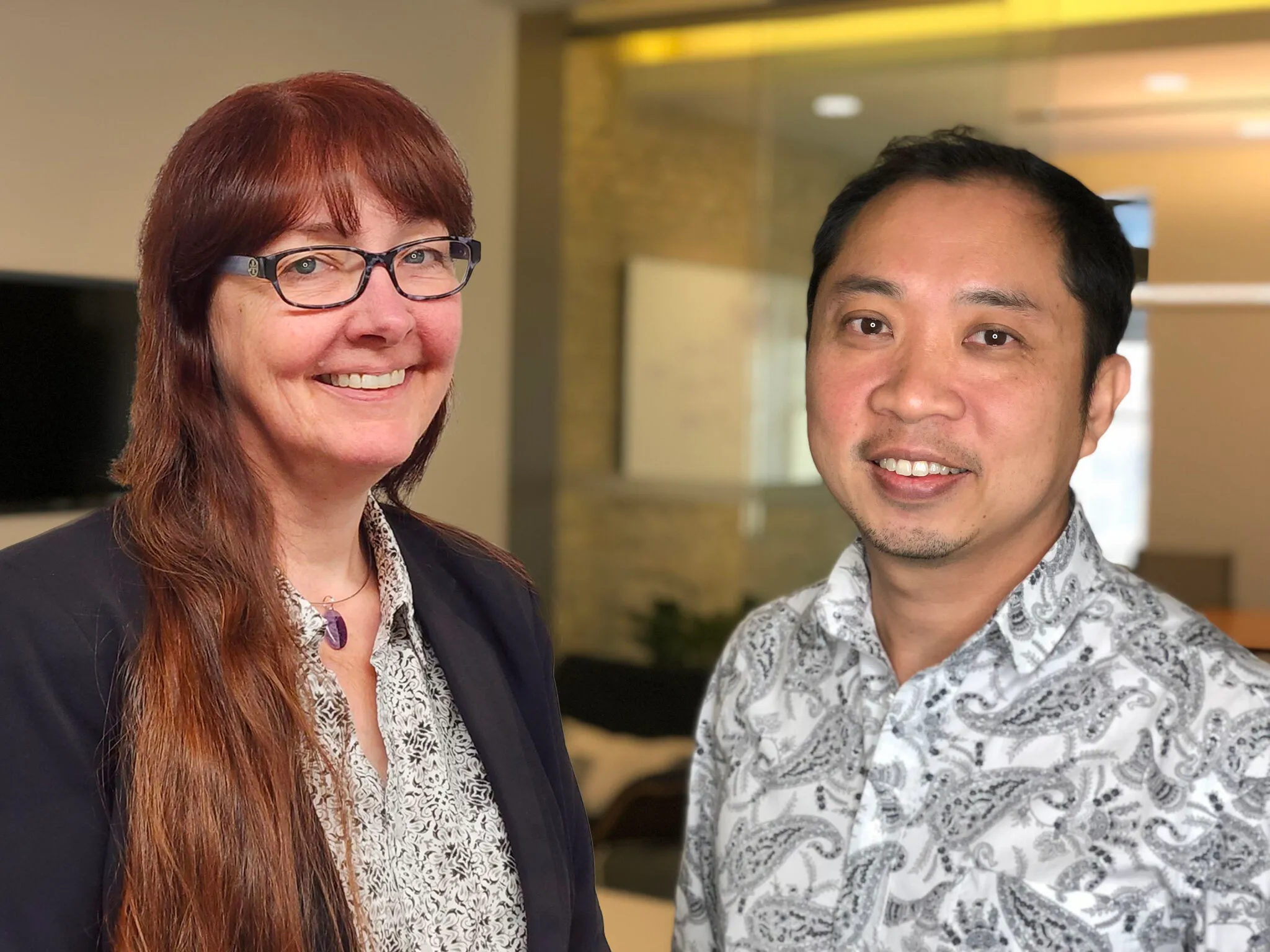 A woman and a man are standing in front of a window.