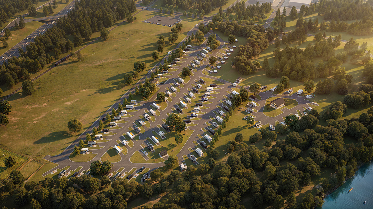 Aerial view of an RV park with rows of RVs parked on paved lots surrounded by trees and green fields near a lake.