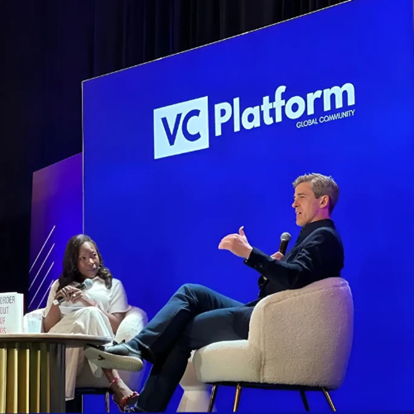 Scott Walker on stage in armchairs having a discussion with microphones in front of a blue VC Platform backdrop.