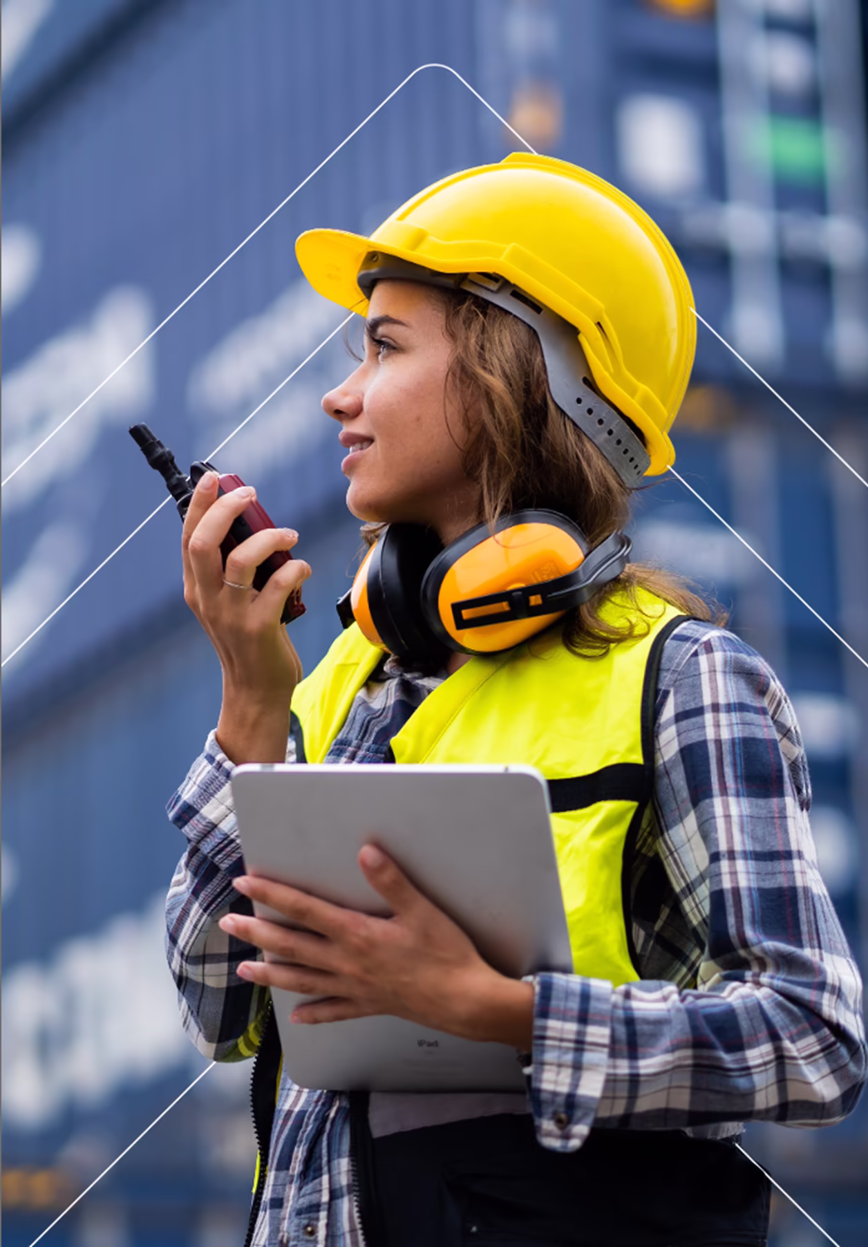 Obrera de la construcción con casco amarillo y chaleco de seguridad, sosteniendo una tableta y utilizando un walkie-talkie.