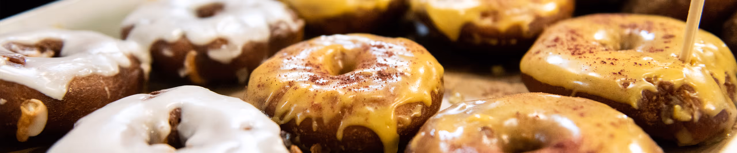 Close-up of assorted glazed donuts with white and yellow icing sprinkled with cinnamon.
