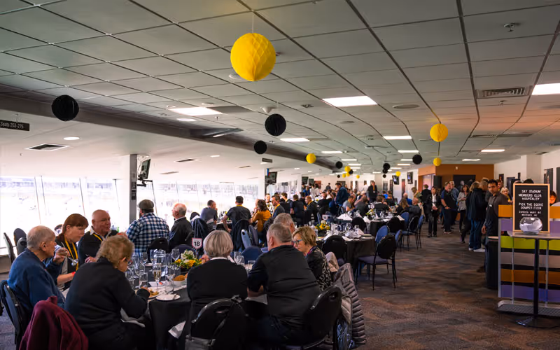 Large indoor lounge filled with people seated at tables enjoying a meal, decorated with hanging yellow and black paper lanterns.