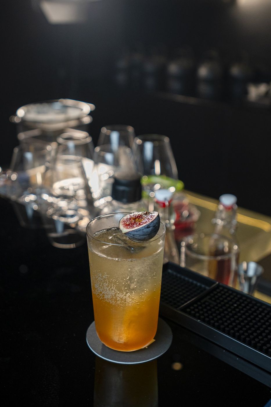 A tall cocktail with a slice of fig on the bar at FOOM, Johor Bahru