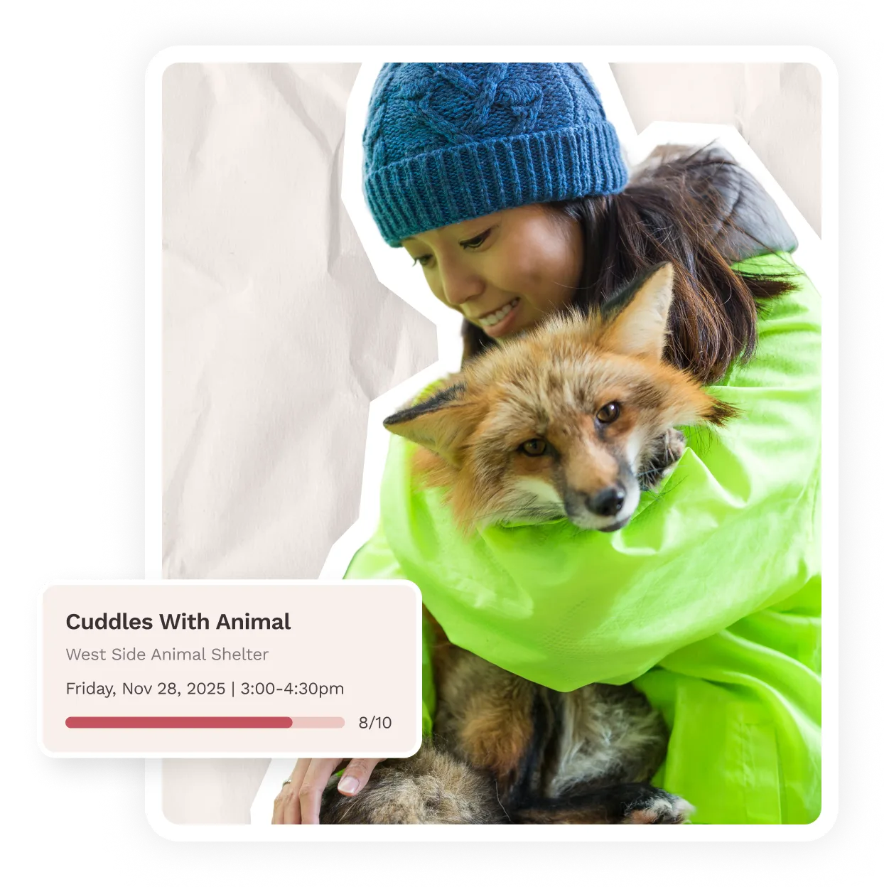 Person in blue knit hat and green jacket cuddling a red fox.