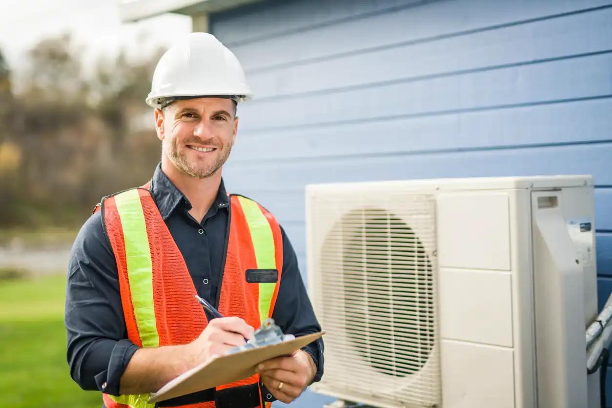 Professional HVAC technician in a safety vest holding a clipboard during an AC unit inspection.