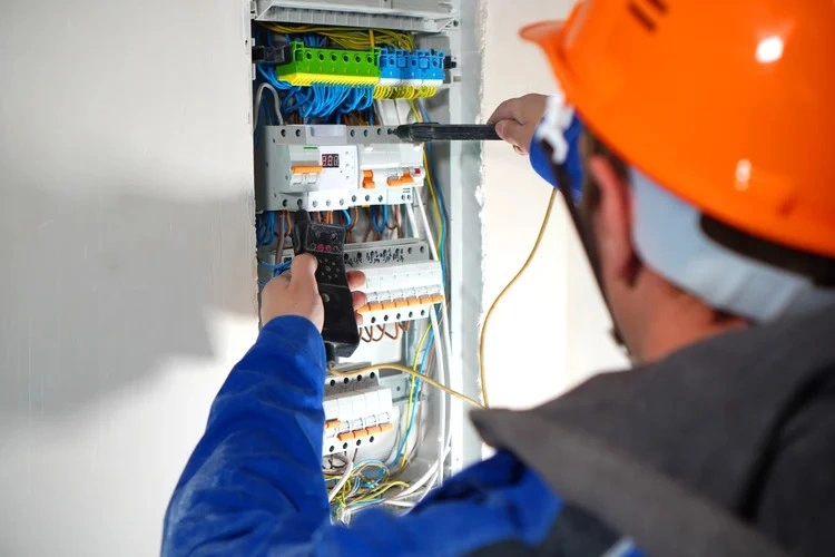 Electrician testing breakers with voltage tester.