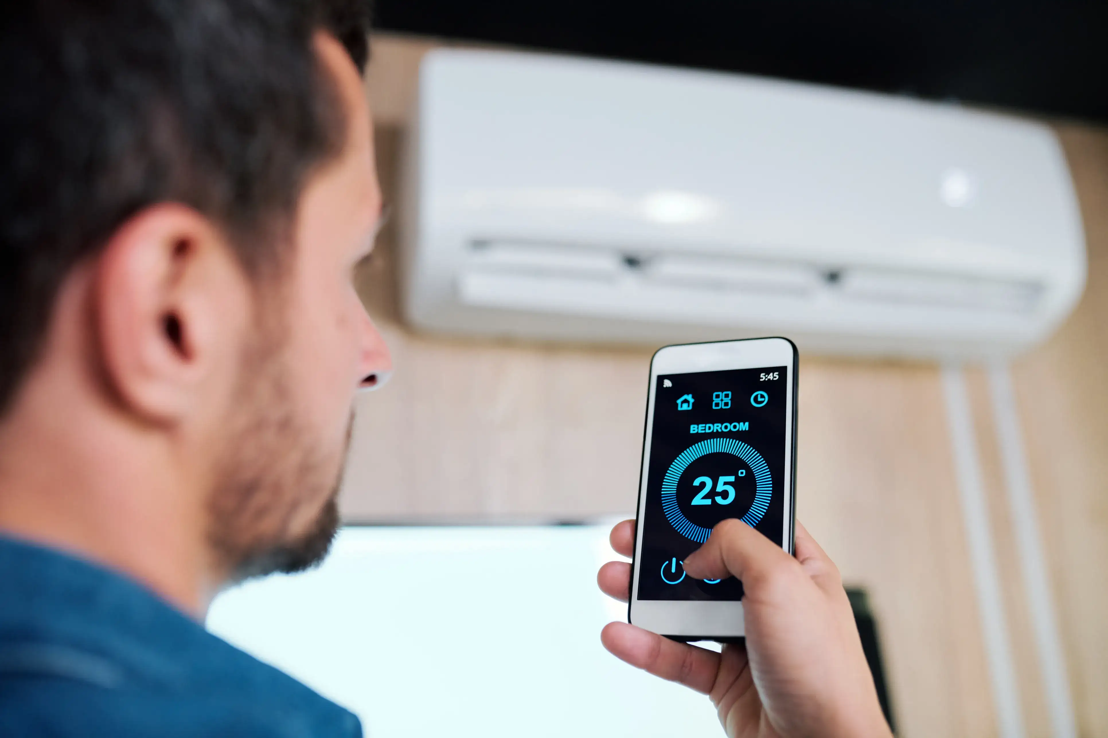 Man using a smartphone app to control a split-system air conditioner.