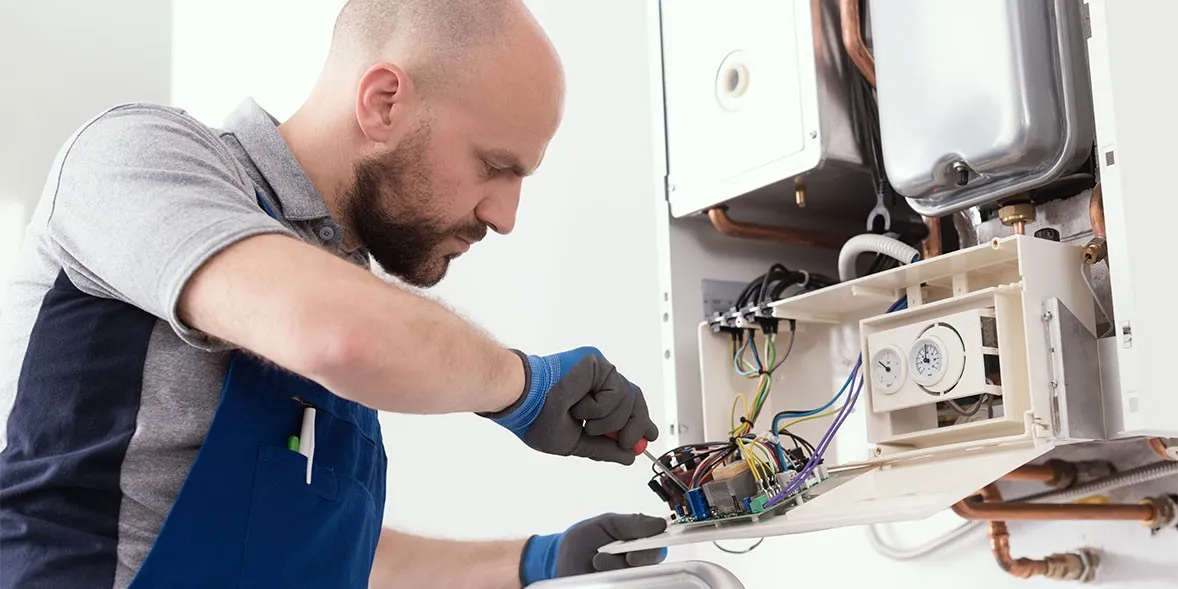 Professional repairing boiler unit electrical wiring.