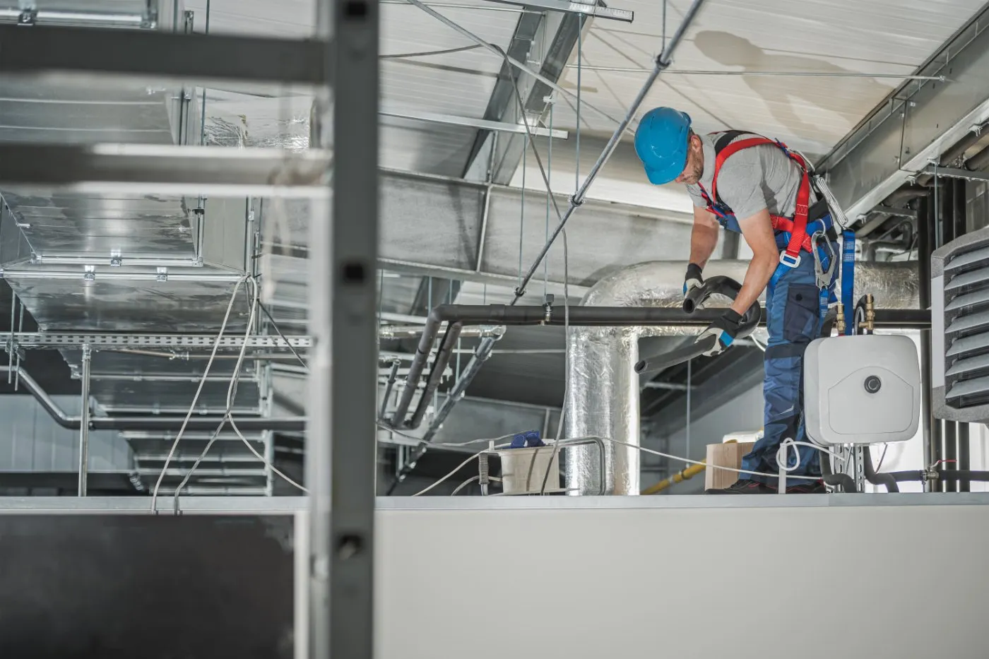 Worker installing indoor commercial HVAC systems.