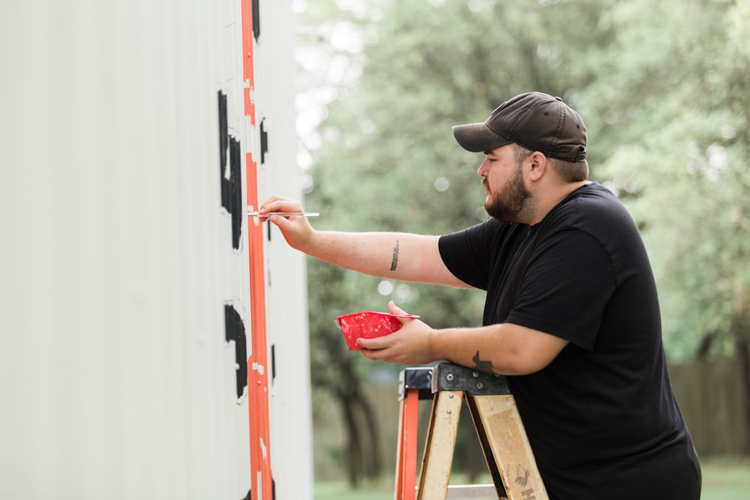 Homeowner installing custom-fit plywood storm shutters over large windows - protecting your home during windstorms and rain Homeowner installing custom-fit plywood storm shutters over large windows - protecting your home during windstorms and rain