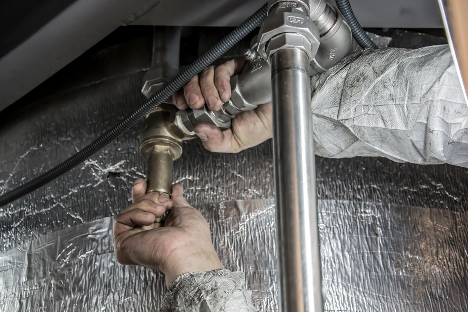 A professional plumber in a clean work area installing a new water heater unit - affordable water heater replacement in A professional plumber in a clean work area installing a new water heater unit - affordable water heater replacement in