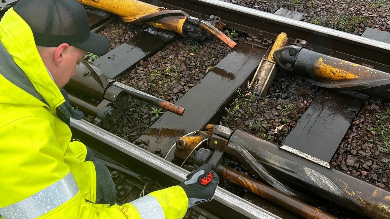 Tekniker i varselkläder arbetar med en DECEL spårbroms på Helsingborg rangerbangård