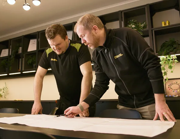 Two DECEL engineers reviewing a technical drawing together in the office