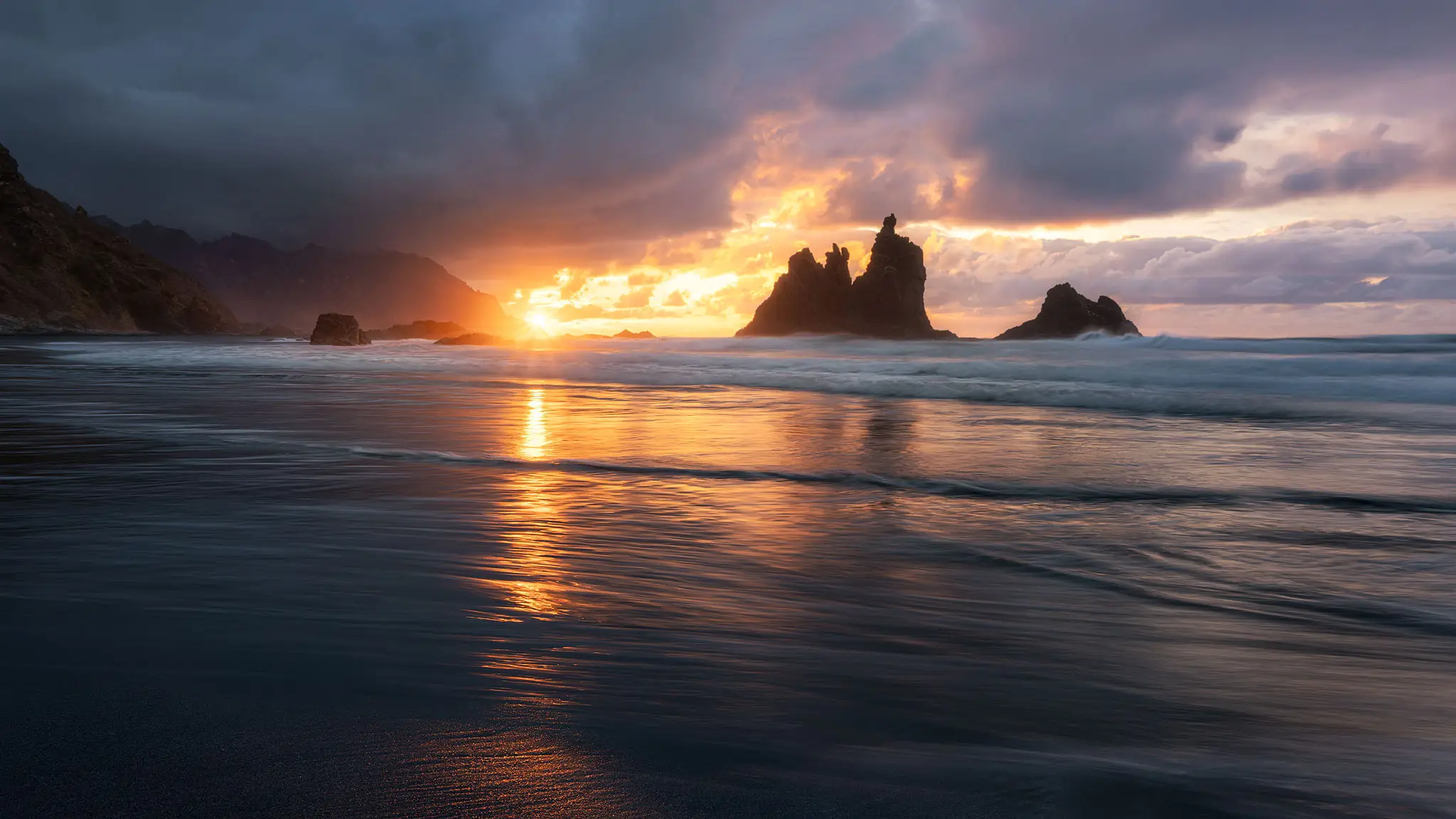La playa de Benijo al atardecer, ya revelada: el sol asomando entre los roques, el reflejo dorado sobre la arena mojada y las olas en movimiento