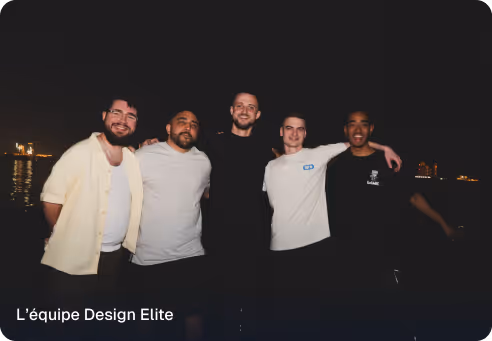 Five men standing close together at night with city lights in the background, smiling at the camera.