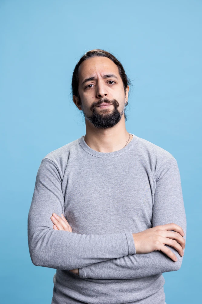 Portrait of man in light sweater smiling with beard.