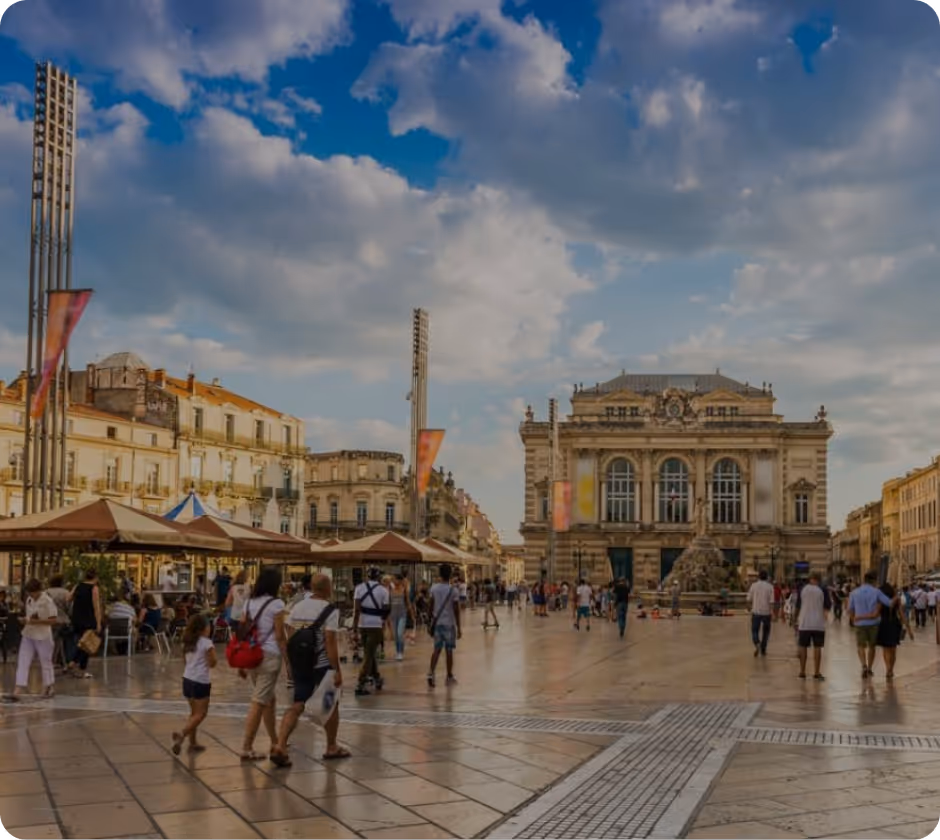 Tramway moderne circulant sur des rails dans une place bordée de bâtiments historiques sous un ciel bleu clair.