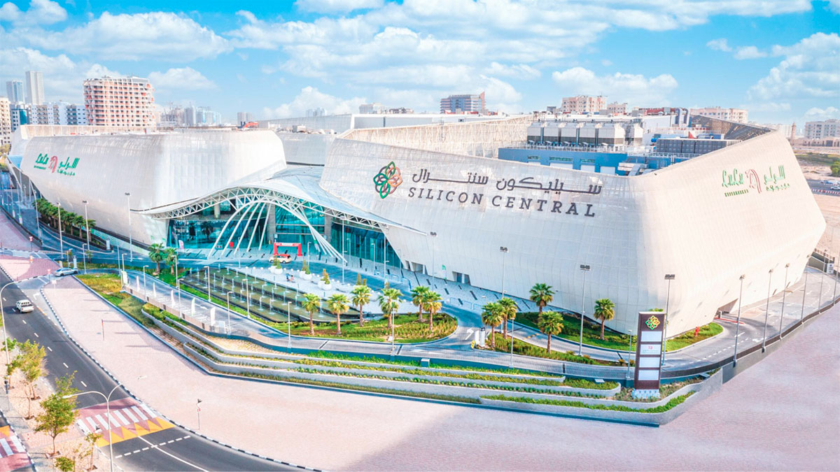 Aerial view of Silicon Central mall in Dubai Silicon Oasis, showing the white shopping centre building, landscaped entrance, roads and surrounding residential towers