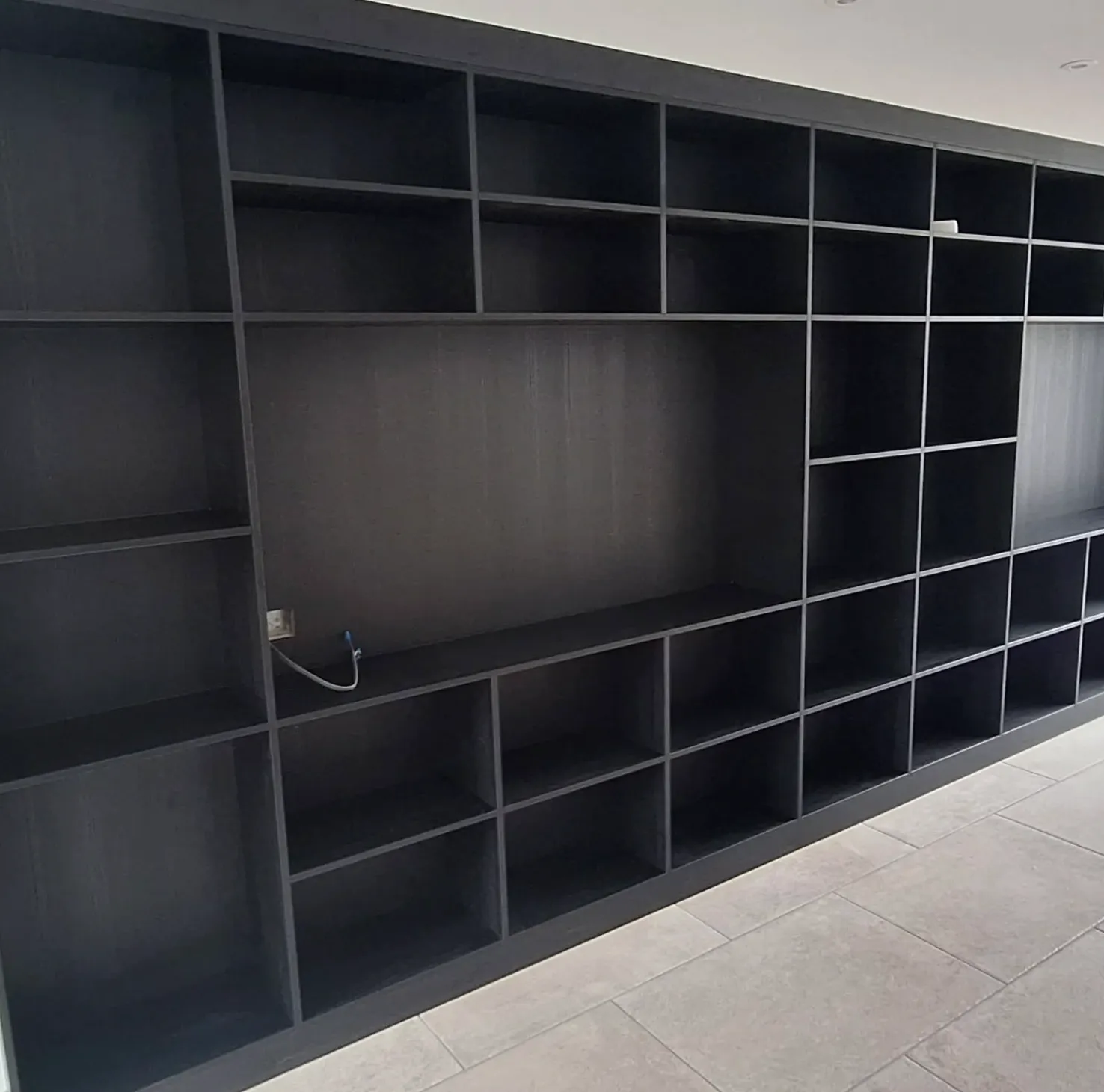 Large black empty modular shelving unit with multiple square and rectangular compartments along a tiled floor in South Yorkshre