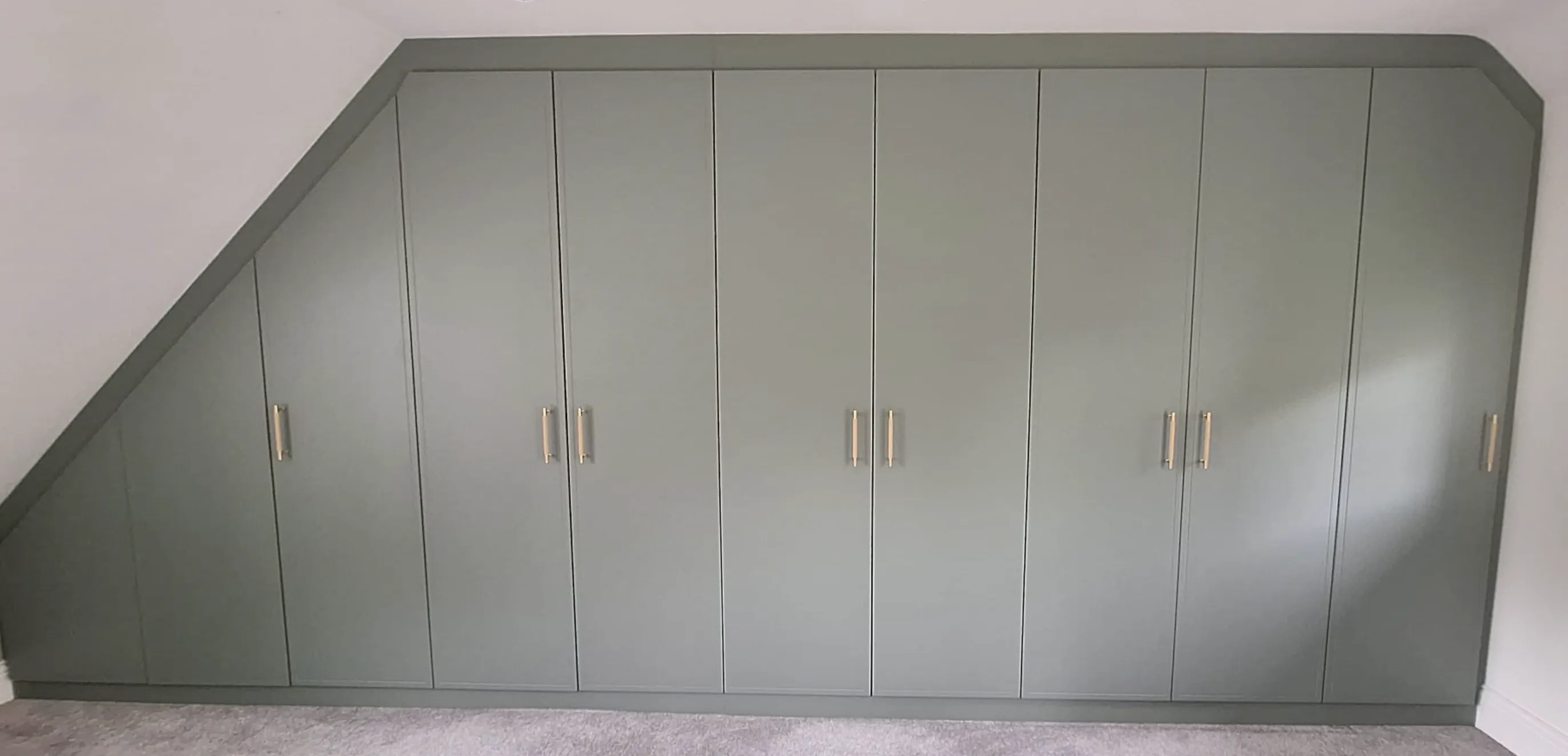 Custom built-in grey wardrobe with angled edges fitting under a sloped ceiling in Penistone