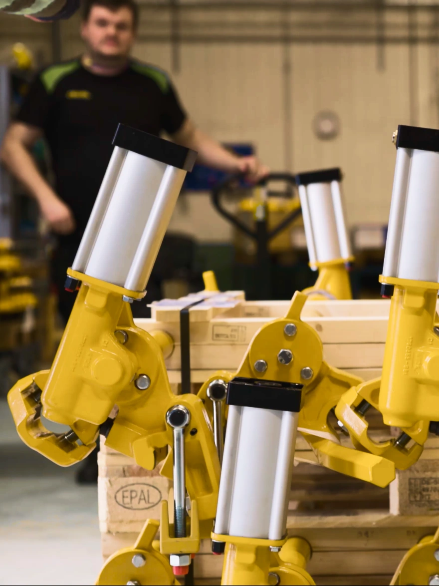 Yellow DECEL spiral retarder units stacked on a pallet in the workshop, with an employee in the background.