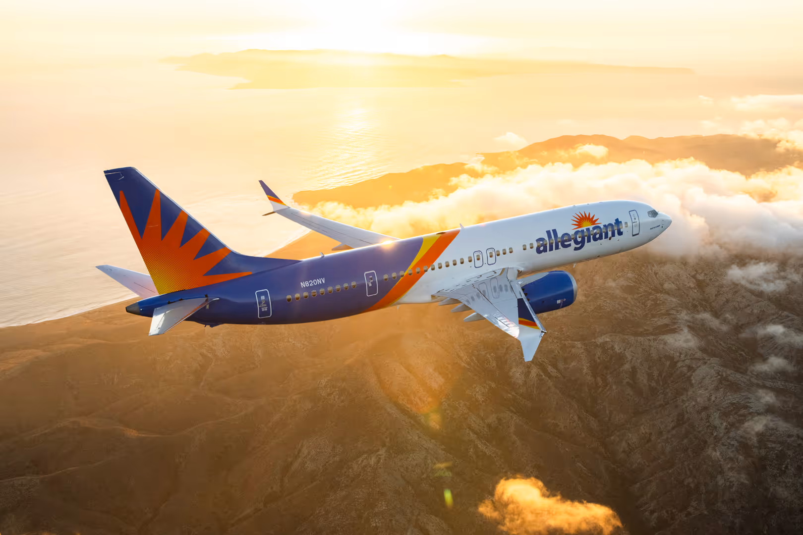 Allegiant Air passenger plane flying over mountainous terrain with clouds and sunset light.