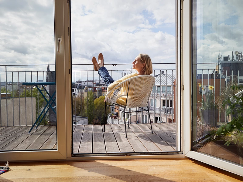 kvinde på balkon med benene slået op på bord