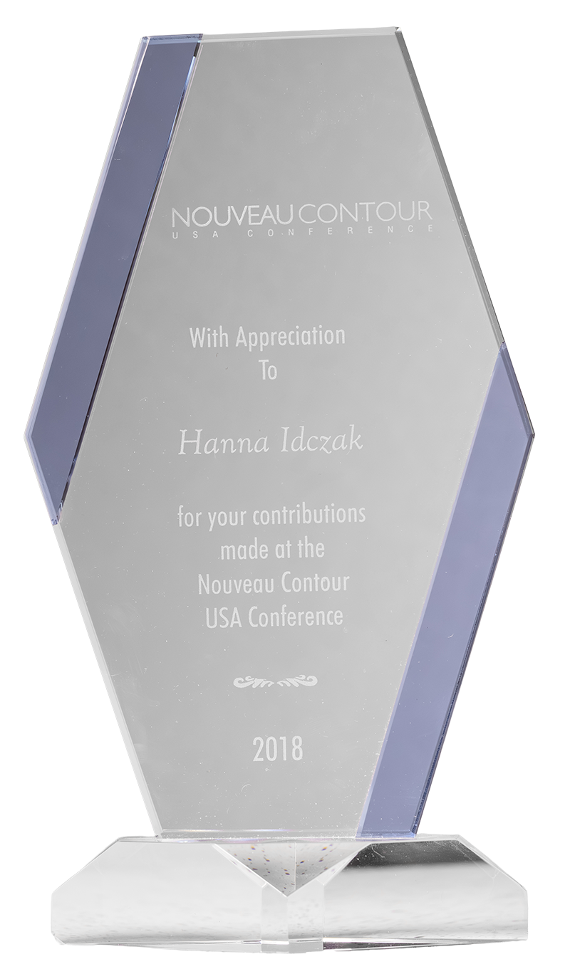Szklana statuetka z napisem: 'Nouveau Contour USA Conference, z wdzięcznością dla Hanny Idczak za wkład wniesiony na konferencji Nouveau Contour USA, 2018'.