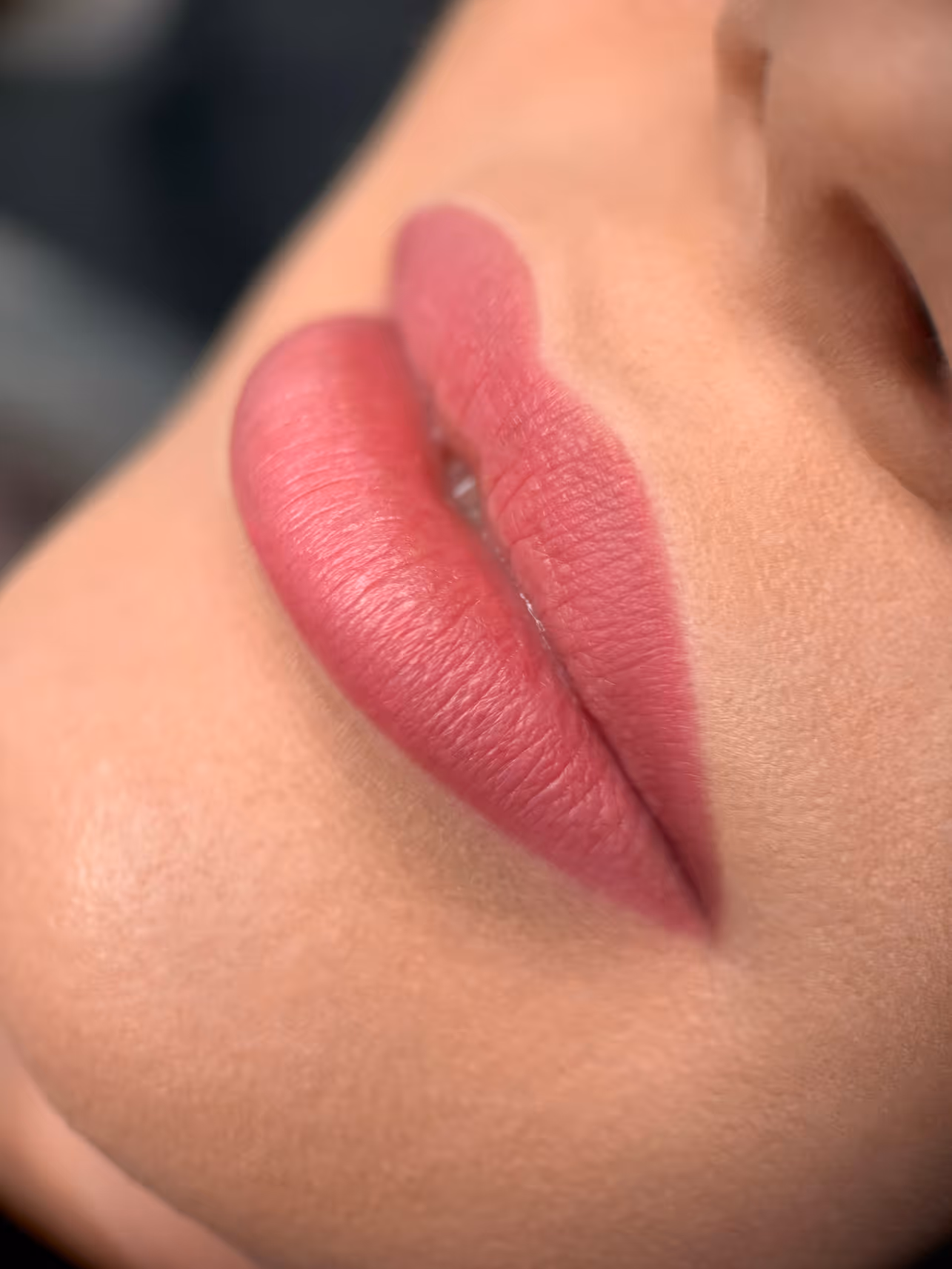 Zbliżenie na usta z różowym matowym makijażem na jasnej cerze.
