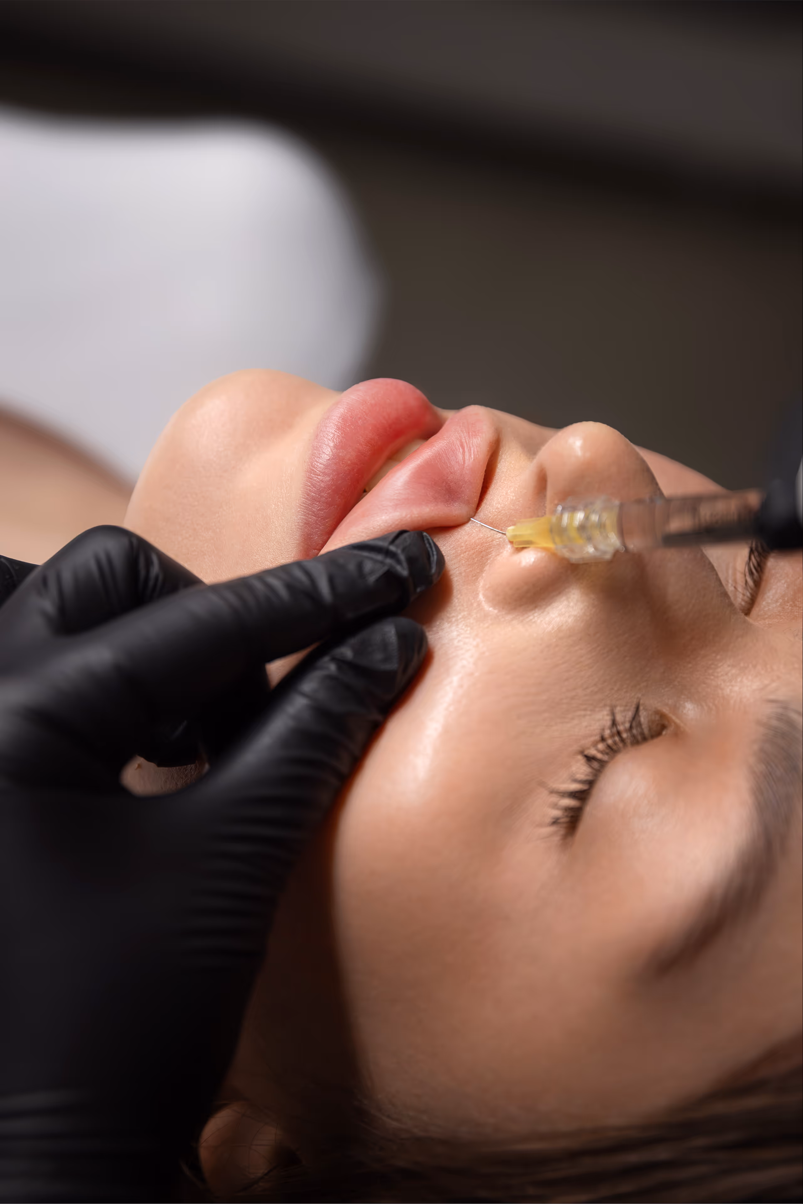 Zbliżenie na kobietę otrzymującą zastrzyk w policzek podczas zabiegu medycyny estetycznej.