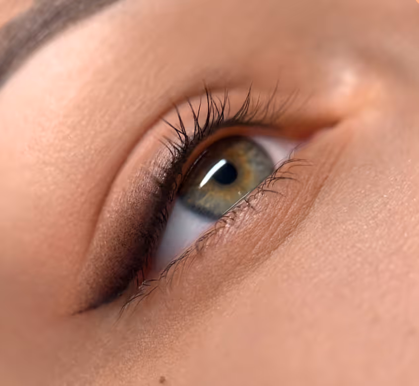 Zbliżenie na zielono-brązowe oko z długimi rzęsami i delikatnym makijażem.