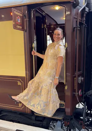 Barrett woman in a light patterned dress stepping out of a vintage train car.
