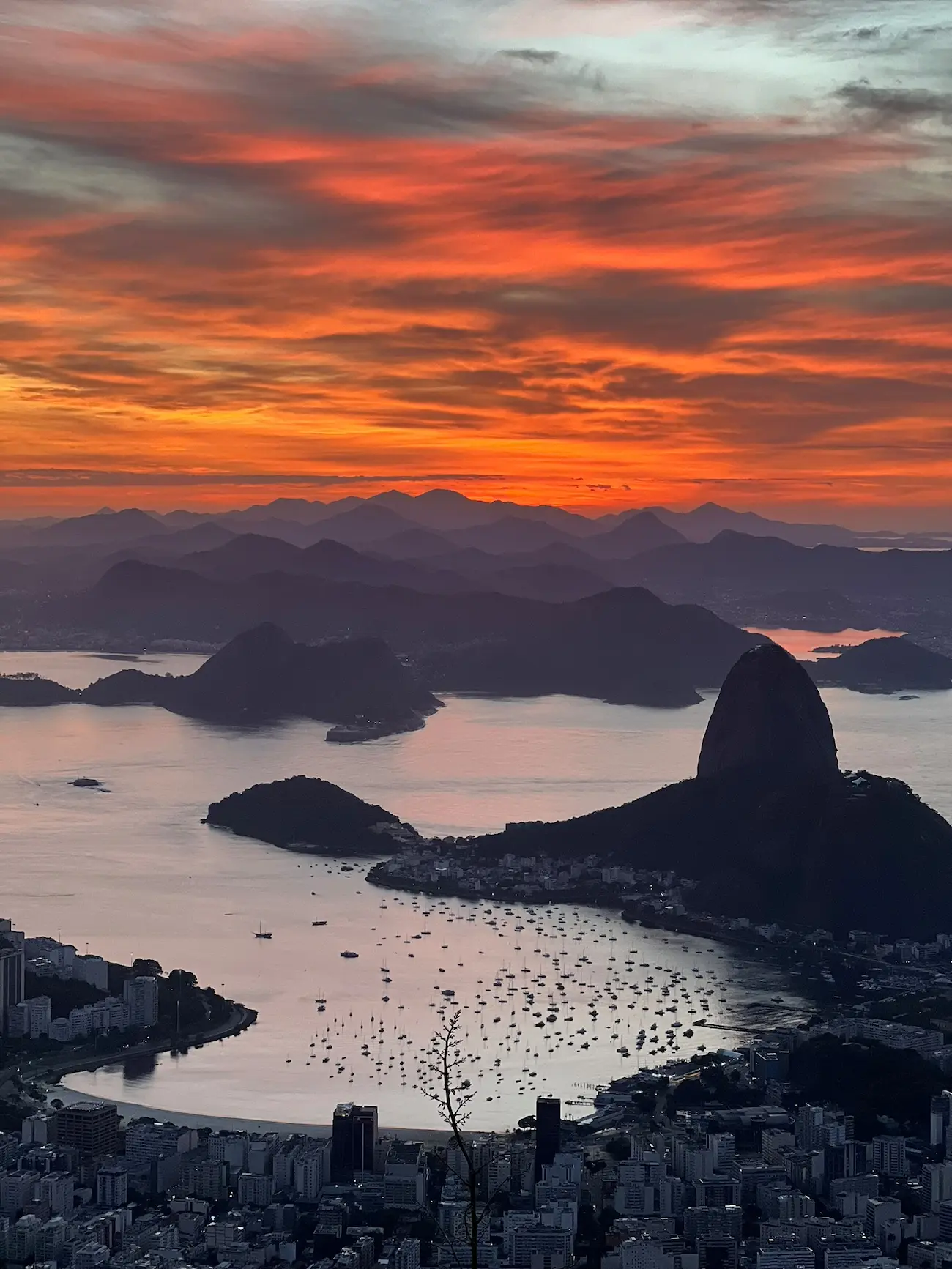 Sunset over Rio de Janeiro with the Sugarloaf Mountain silhouetted and boats anchored in the bay.