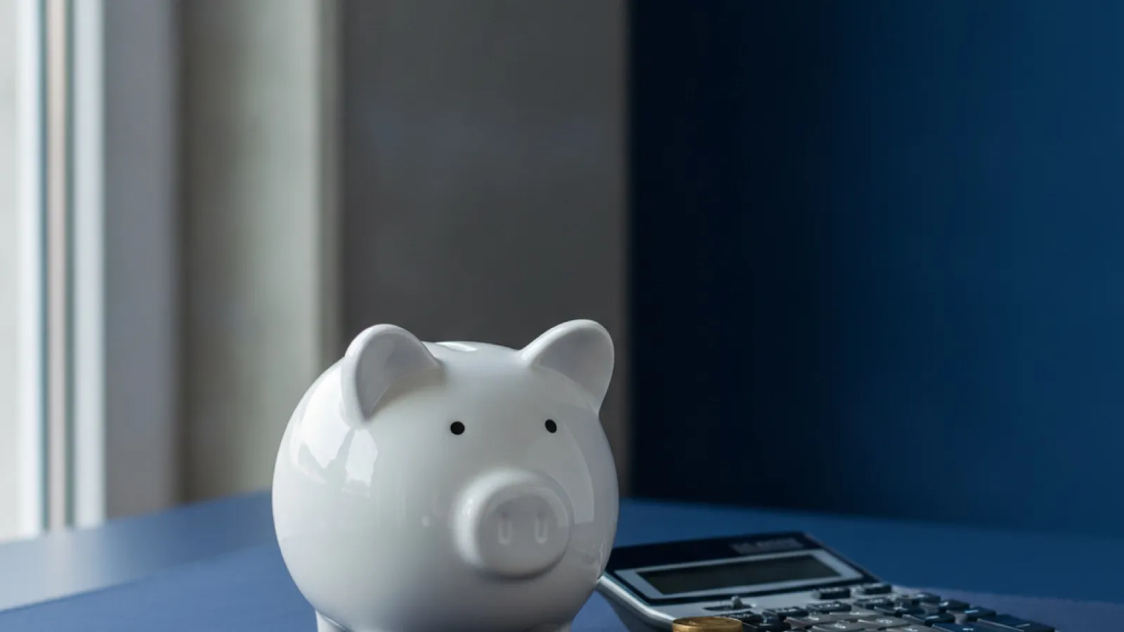 Calculator beside a piggy bank